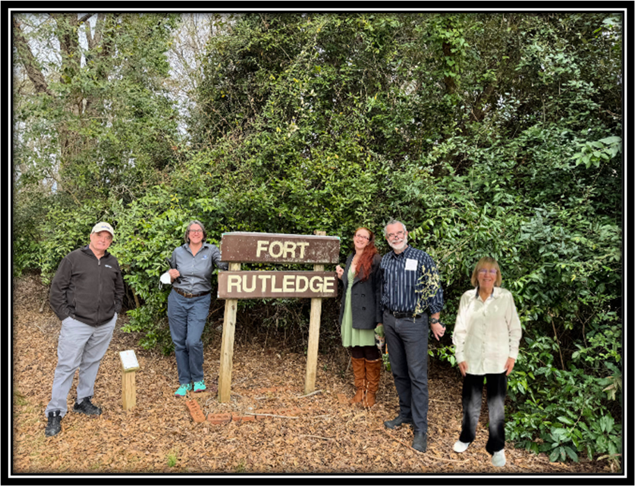 Five people gathered around Fort Rutledge sign in woods